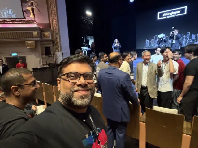 Selfie in a theatre auditorium with a standing crowd and the AI Engineer Singapore logo on the stage screen