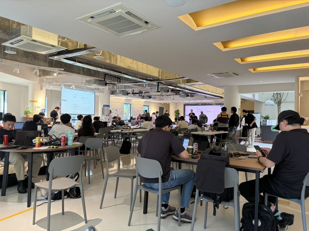 Hackathon build floor in Singapore with teams working at long tables