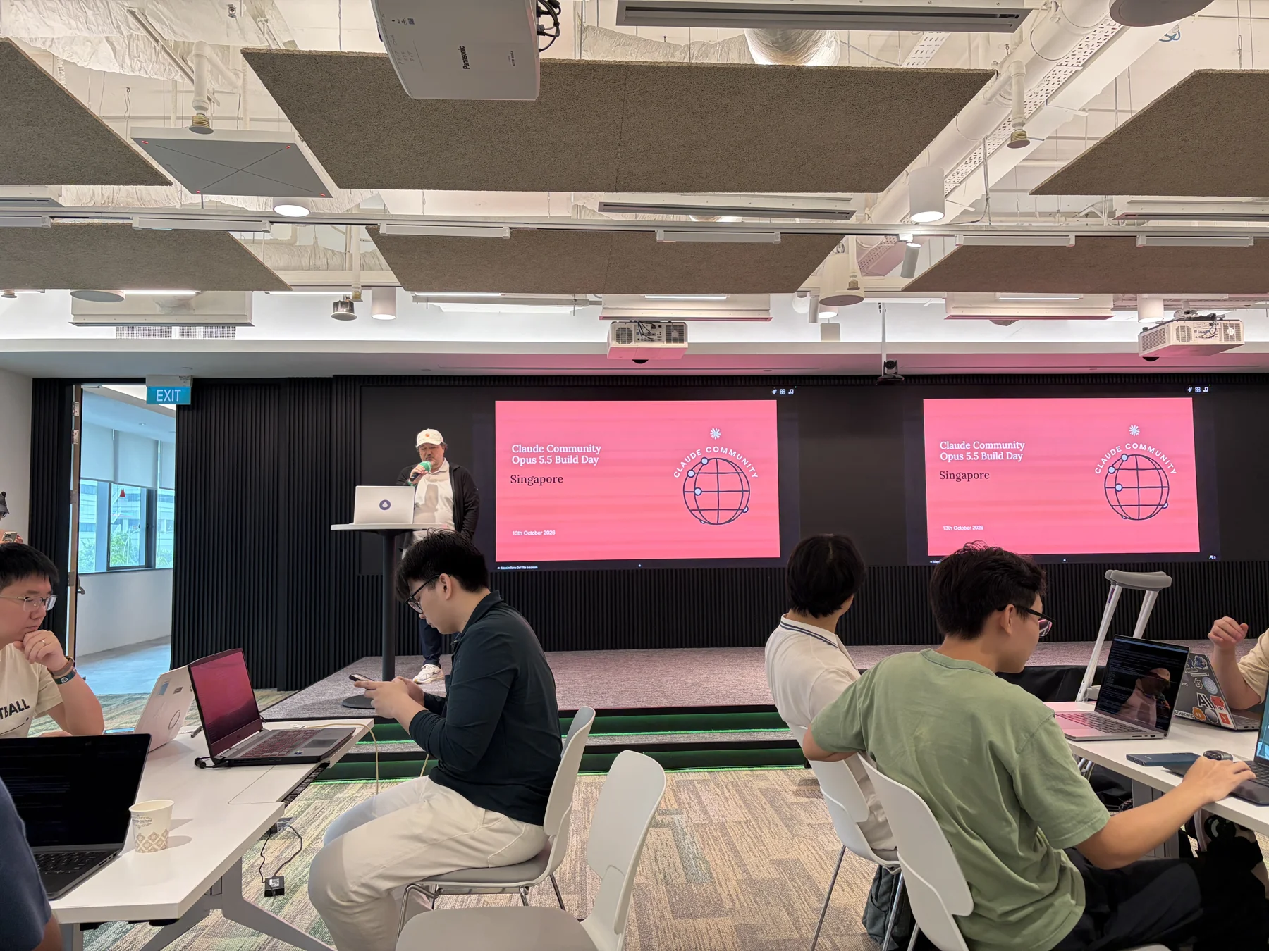 Builders at tables in front of the stage showing Claude Community Opus 5.5 Build Day, Singapore, 13 October 2026