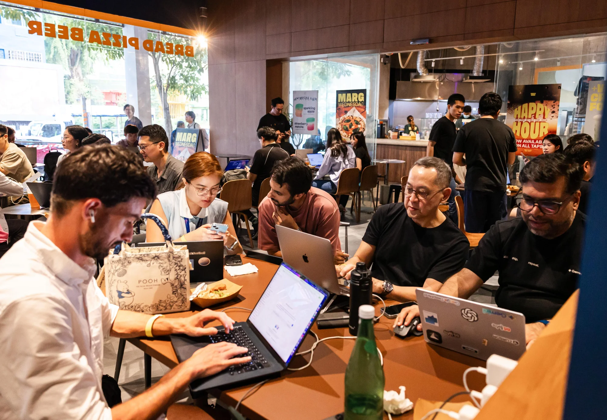 People building together around crowded tables with laptops open at the hackathon